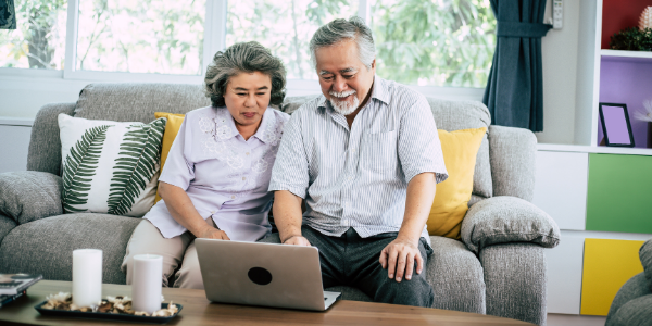 Older Asian couple plans for retirement using age banding on laptop computer